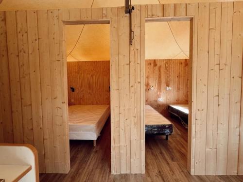 a room with two beds in a wooden cabin at Camping 4 étoiles - Piscine - ccbgbac in Arques