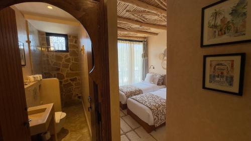a bedroom with two beds and a bathroom with a mirror at Palm Surf & Spa Hotel in Agadir