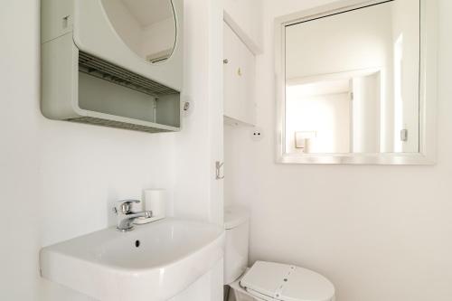 a white bathroom with a sink and a mirror at 30m to Beach - Mindelo Ocean House in Mindelo