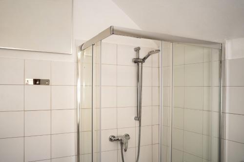a shower in a bathroom with white tiles at La corte del Lago in Sulzano