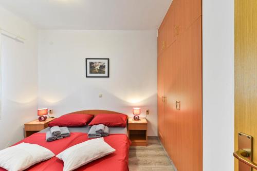 a bedroom with a red bed and two desks at Apartmani LUNA in Vir