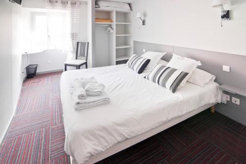 a bedroom with a large white bed with towels on it at Auberge Le Cantou - Hôtel Roche in Orcival