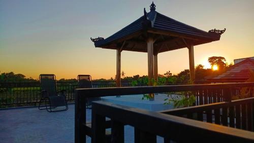 a swimming pool with a gazebo and a sunset at VILLA PAPA PUTU in Banjar