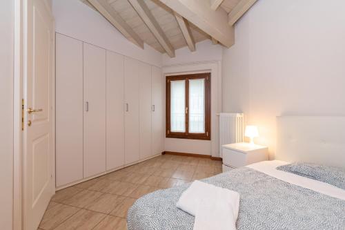 a white bedroom with a bed and a window at Trilocale Rua Sovera 85 - F&L Aparment in Brescia