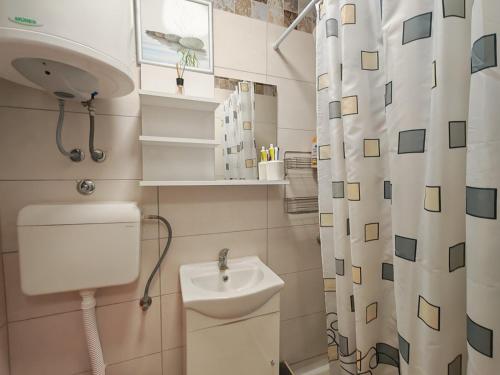 a bathroom with a sink and a shower curtain at Apartman Lola Ruža in Zrenjanin