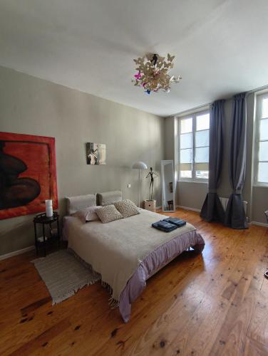 a bedroom with a bed and a chandelier at Chez Marie, maison ArtY in Lauzun