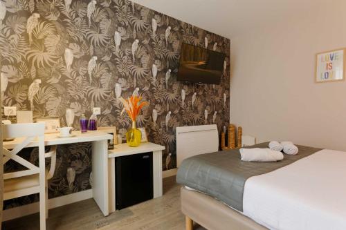 a bedroom with a bed and a desk with a desk at La glycine hotel, spa et bien-être in Bénouville