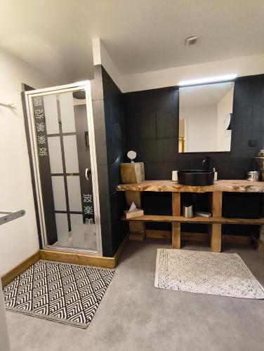 a bathroom with a sink and a shower with a mirror at Chez Marie, maison ArtY in Lauzun