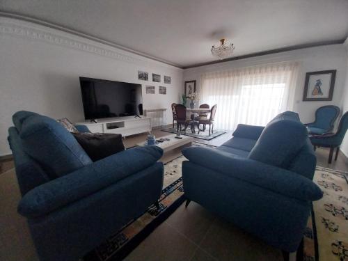 a living room with blue couches and a tv at GuestHouse Pombinha in Nazaré