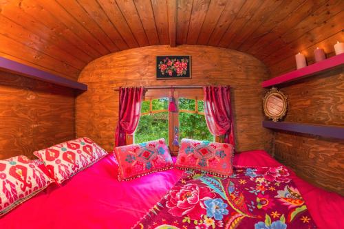 a room with a pink bed with pillows and a window at Roulotte du Rouard in Camiers
