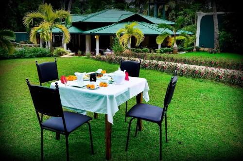 a table with a white tablecloth and four chairs at The Kings Villa in Kandy
