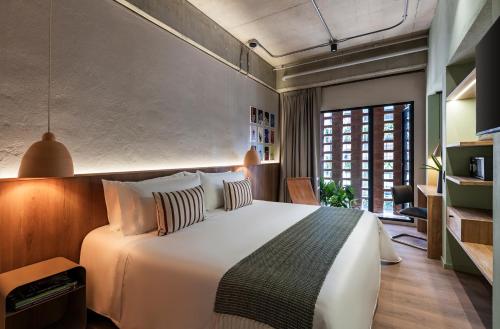 a bedroom with a large white bed with pillows at Obra Hotels in Medellín