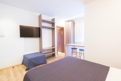 a bedroom with a bed and a tv and a table at Essenza Residence in Cervia