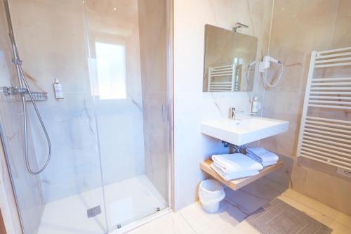 a white bathroom with a shower and a sink at Essenza Residence in Cervia