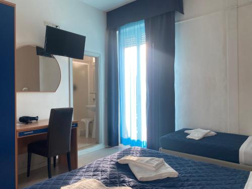 a hotel room with a bed and a desk and a mirror at Hotel New Primula in Rimini
