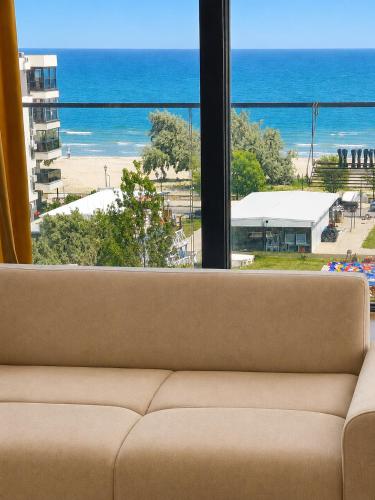 a couch in front of a window with a view of the beach at Italy Luxury Apartment front of the sea in Mamaia Sat/Năvodari