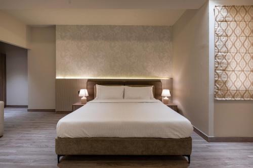 a bedroom with a large bed and two lamps at Mansions by HomeSlice in Bangalore