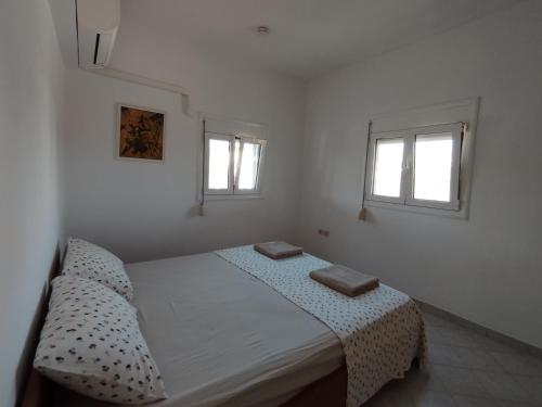 a white bedroom with a bed and two windows at Marias Apartment in Kolymbia