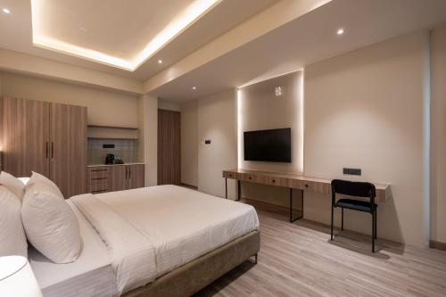 a bedroom with a bed and a desk with a television at Mansions by HomeSlice in Bangalore