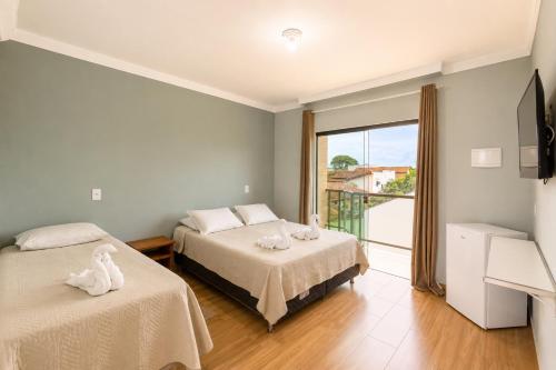 a bedroom with two beds and a balcony at Pousada Voo das Garças in Bonito