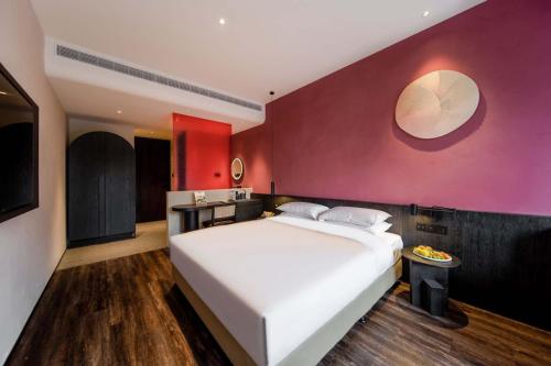 a bedroom with a white bed and a red wall at M Hotel in Hangzhou
