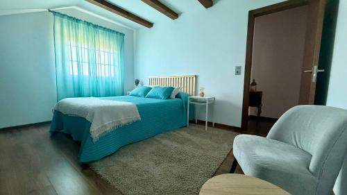 a bedroom with a blue bed and a chair at Casa Eira de Arriba - by entreRías in Cangas de Morrazo
