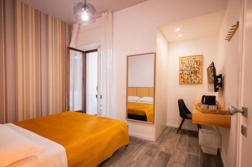 a hotel room with a yellow bed and a desk at Garibaldi Suite B&B in Salerno