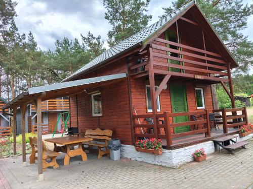 a small wooden cabin with a picnic table and a table at Domki Piaskowa in Boszkowo-Letnisko