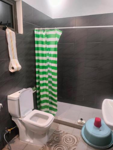a bathroom with a toilet and a green shower curtain at Rob's House in Lalmatie