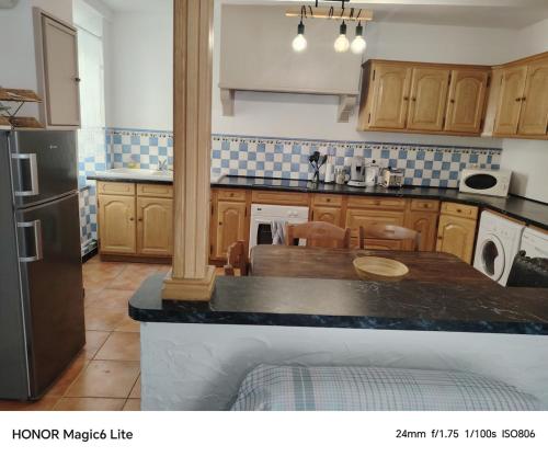 a kitchen with wooden cabinets and a table and a refrigerator at La Casa de Nona in Carcassonne