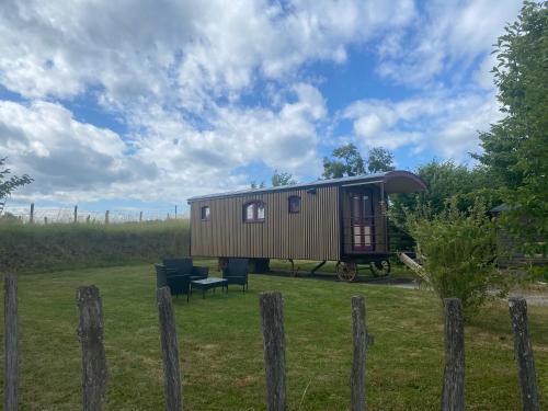 a tiny house in a field with a fence at La Roulotte au Paradis in Arc-et-Senans