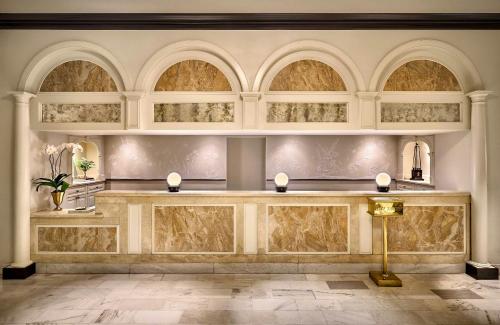 a lobby with a marble counter with arched windows at Omni Royal Orleans Hotel in New Orleans