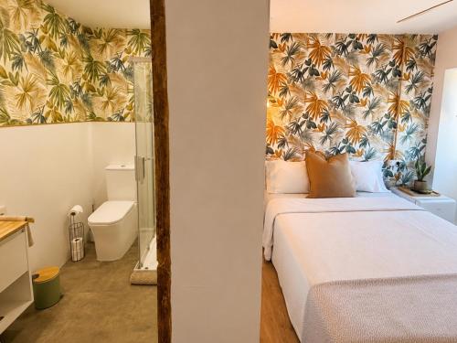 a bedroom with a bed with a tropical wallpaper at Holibai Mirada do Roxo 3 suites y vistas al mar in Oia