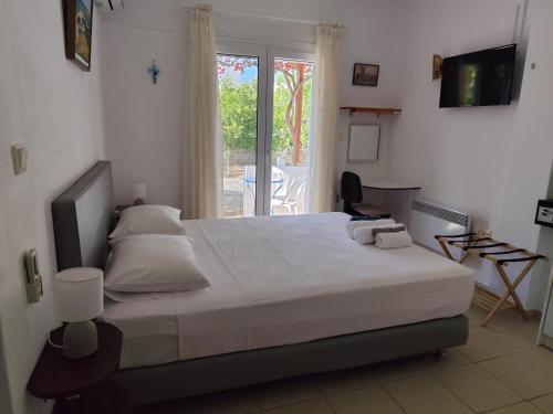 a bedroom with a large white bed and a window at Iro's Cute House in Parikia