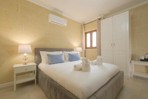 a bedroom with a large white bed with blue pillows at Villa Joanna in Xagħra