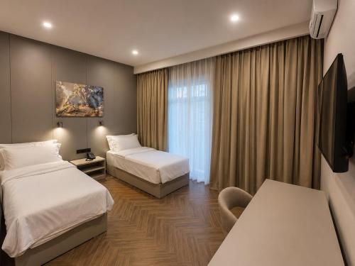 a hotel room with two beds and a television at Delmont hotel in Kostanay