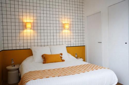 a bedroom with a bed with two lights above it at ARBELLIA Appart'Hôtel Châlons en Champagne in Chalons en Champagne