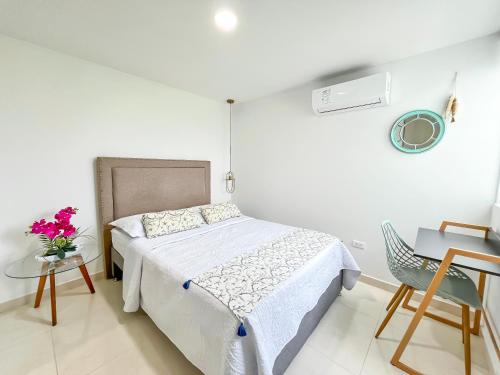 a white bedroom with a bed and a table and chairs at Mirador, Coveñas 302 in Coveñas