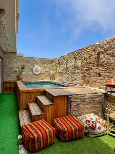 a swimming pool with two stools in front of a house at Zeri Surf Taghazout Hiltop in Taghazout