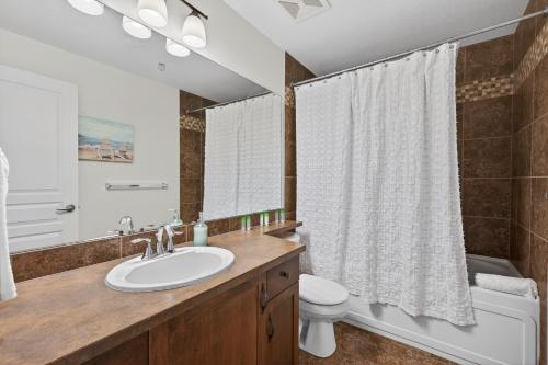 a bathroom with a sink and a toilet and a mirror at Playa Del Sol 2 Bdrm 649 w/ Mountain Views! in Kelowna