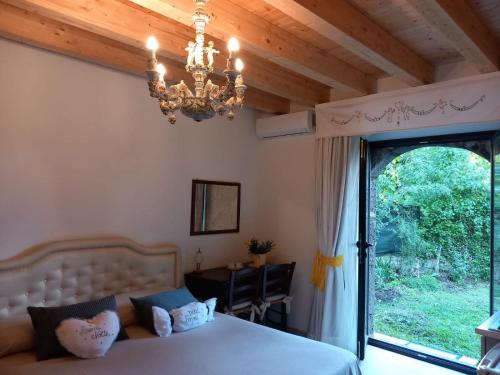 a bedroom with a bed and a chandelier and a window at Riccioli dell' Etna in Piedimonte Etneo