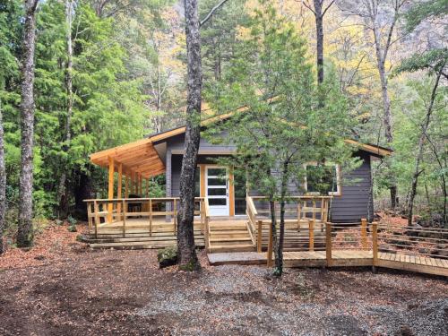 a cabin in the woods with a wrap around porch at Complejo Alto La Invernada in Las Trancas