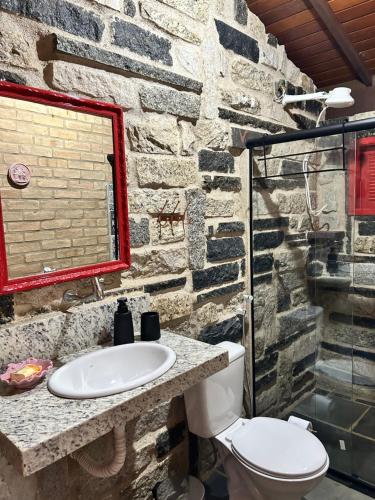 a stone bathroom with a toilet and a sink at Chalé Carrara, um Refúgio de Pedra na Mata - Chalés Flor dos Manacás in Santa Teresa