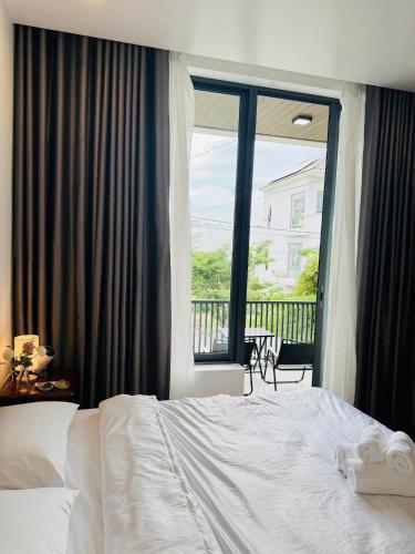 a bedroom with a white bed and a large window at NÚP Homestay Huế in Thôn Dương Xuân Hạ