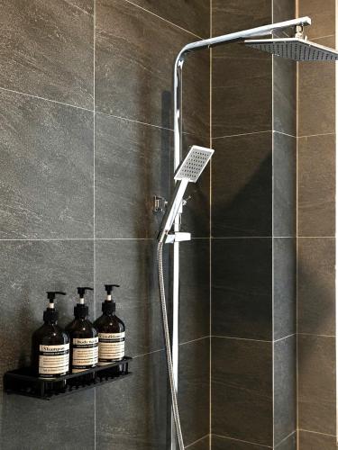 a shower with three bottles on a shelf in a bathroom at NÚP Homestay Huế in Thôn Dương Xuân Hạ