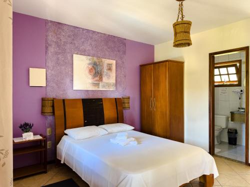 a bedroom with a white bed and purple walls at Pousada Tempo Rei in Boicucanga