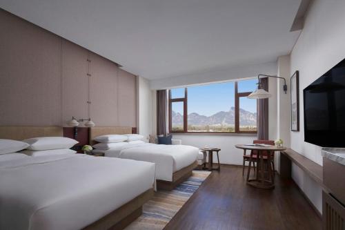 a hotel room with two beds and a flat screen tv at Beijing Marriott Hotel Yanqing in Yanqing