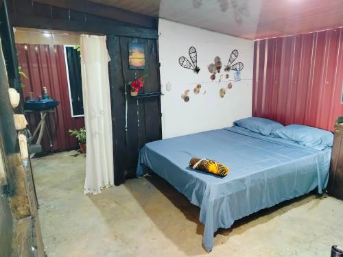 a bedroom with a bed with blue sheets and butterflies on the wall at Bosque celeste in Rio Celeste