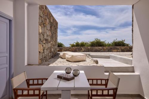a patio with a table and chairs and a stone wall at Milesian Suites in Adamantas