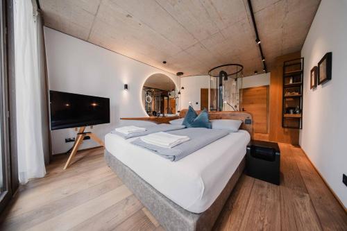 a large white bed in a room with a tv at Boutique-Hotel LARTOR in Unterammergau